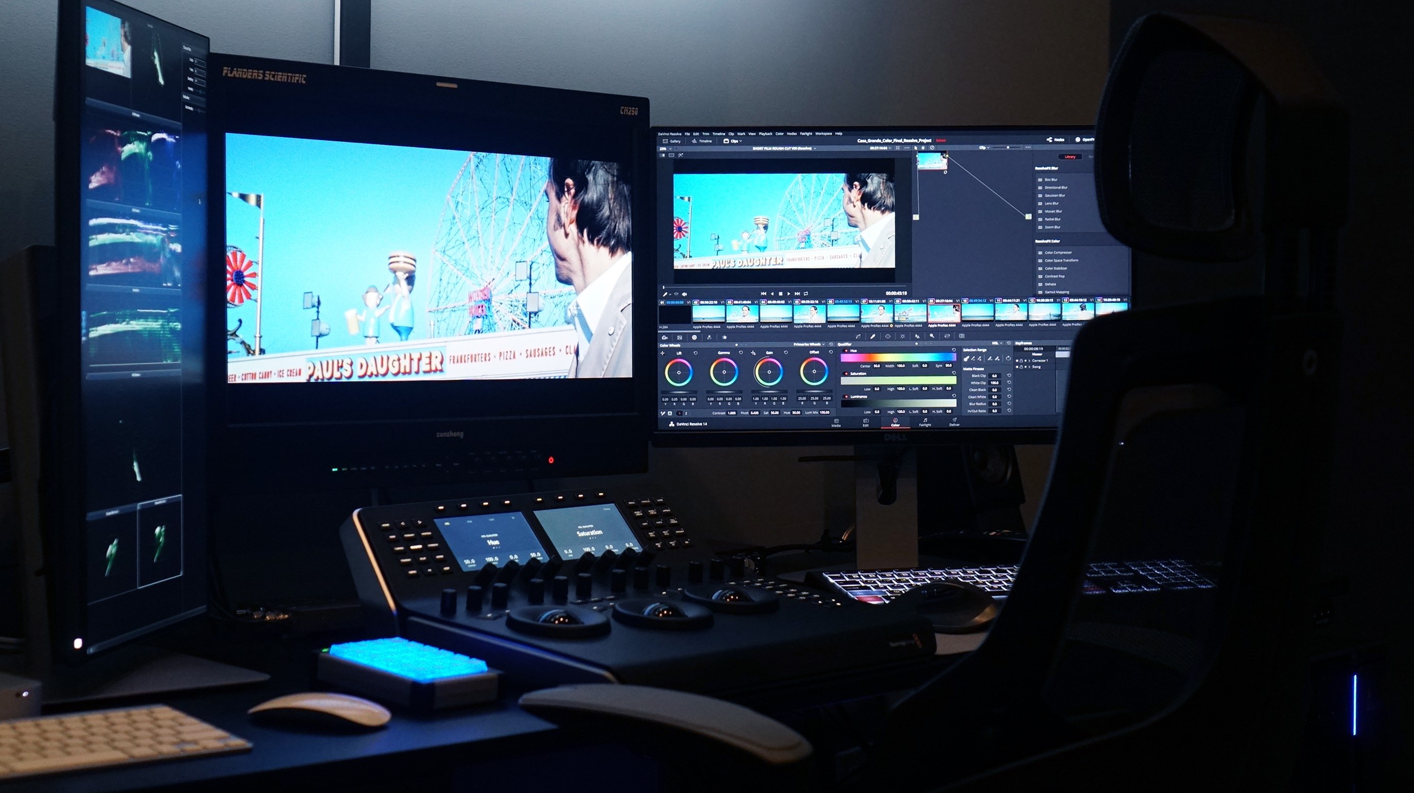 Editor at an Astra Visual Studios edit and colour grading suite, with reference monitors and posters of past projects